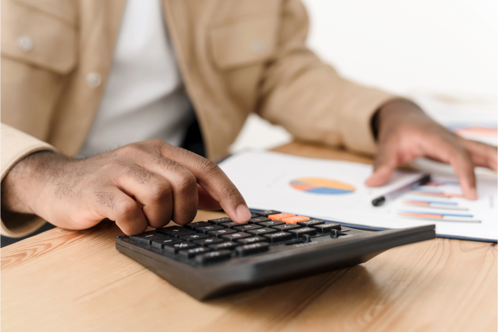 Person reviewing spreadsheet while typing on calculator 