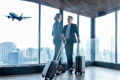 Two people in an airport with a plane flying in the background
